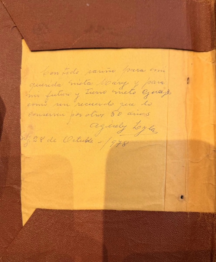 A sheet of yellow paper pasted inside a worn reddish-brown leather cover, with five lines written in pencil, a signature and a date
